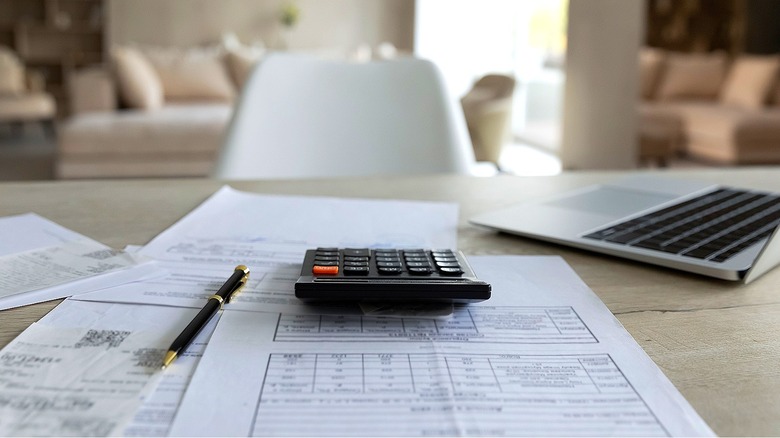 Calculator, laptop, paperwork on table