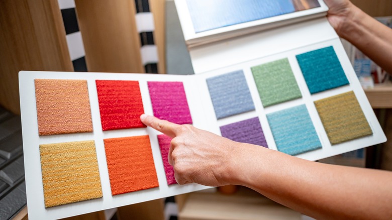 Person pointing at a red carpet sample on a book with multiple samples