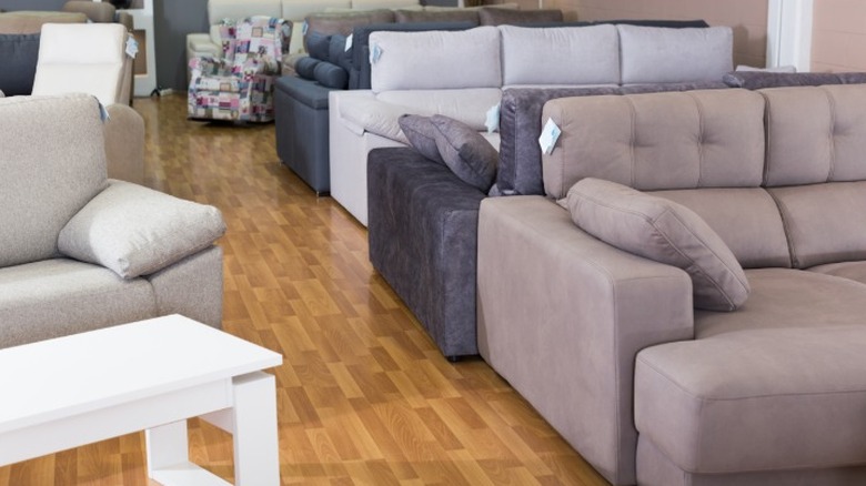 Couches and tables lined up in a furniture store on a wood floor.