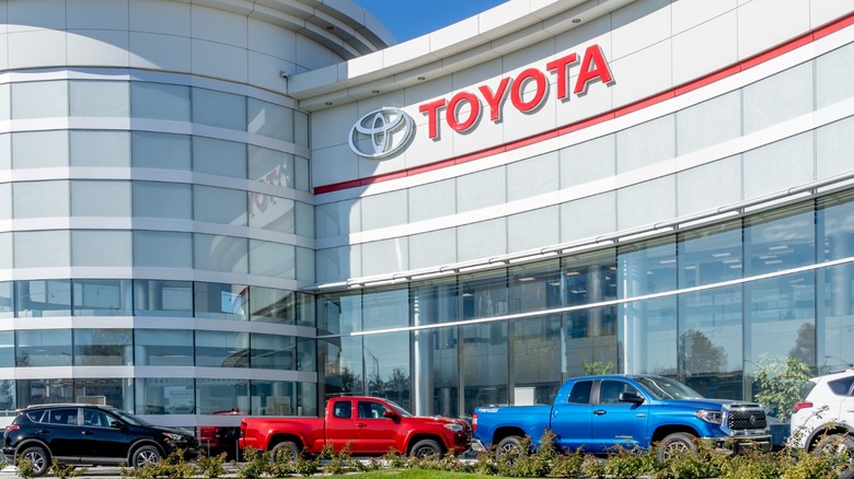 A Toyota office building in North America on a sunny day with Toyota trucks parked outside of it.