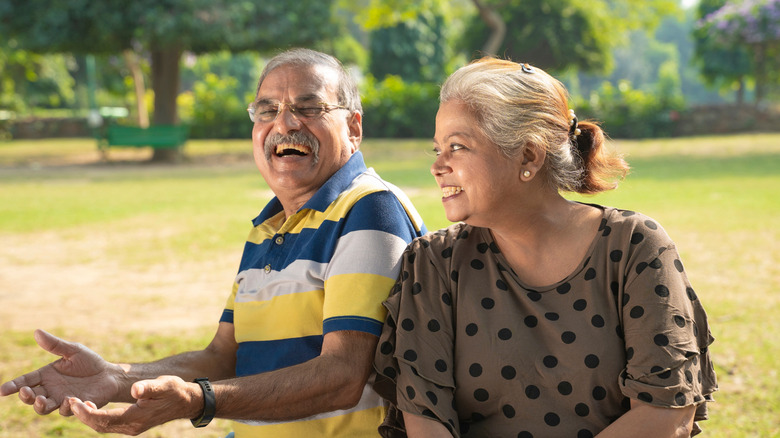 A smiling older couple sitting in a park