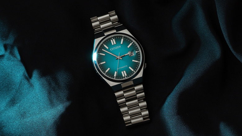 A Citizen Tsuyosa laying against a silky green fabric