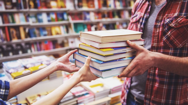 a woman hands books to a customer at a book store