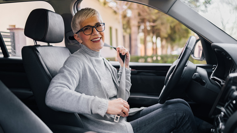 A senior woman getting into a car and connecting a seatbelt