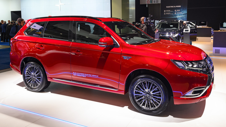 A red Mitsubishi Outlander PHEV parked indoors at a car show.