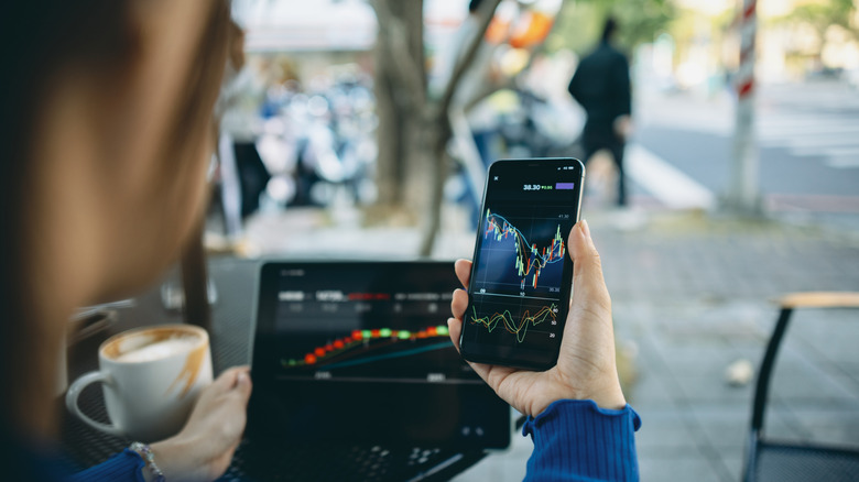 Person holding smartphone displaying stock market charts