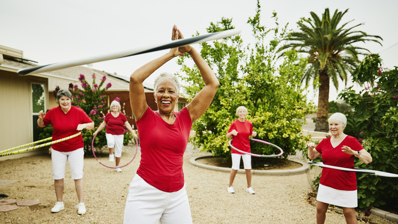 A group of joyful senior women hula hooping in a retirement community.