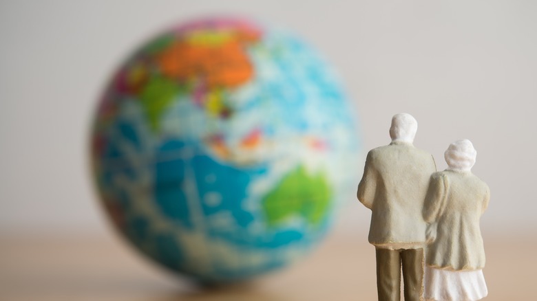 Figures of an old couple looking at a globe of earth