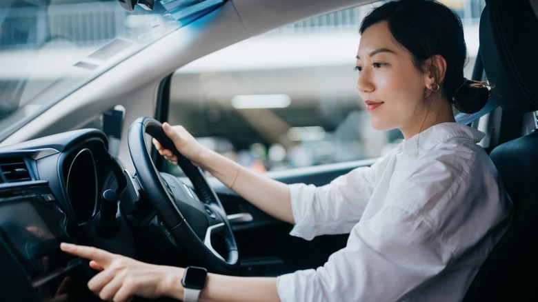 Asian woman activating GPS while in the driver's seat in a car
