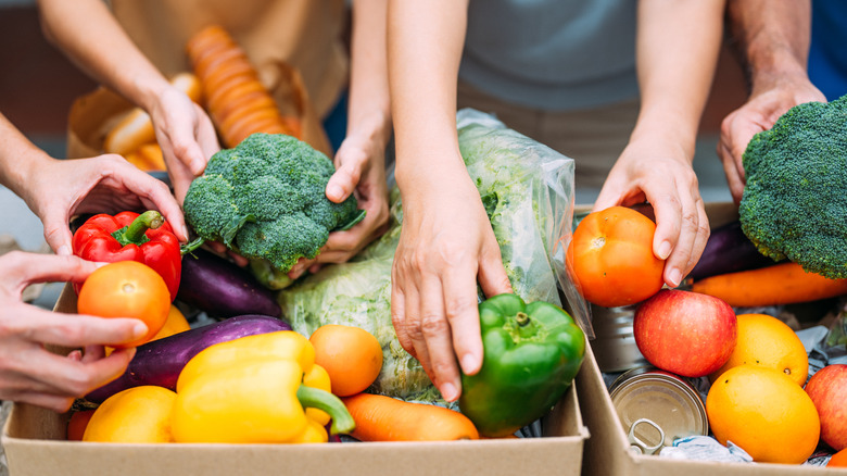 Volunteers' hands pack cardboard boxes full of fresh food and nonperishables