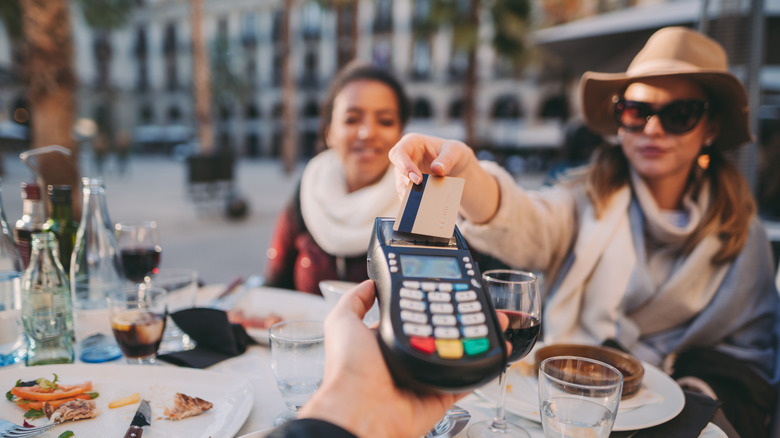 A woman paying a waiter at a restaurant in Barcelona
