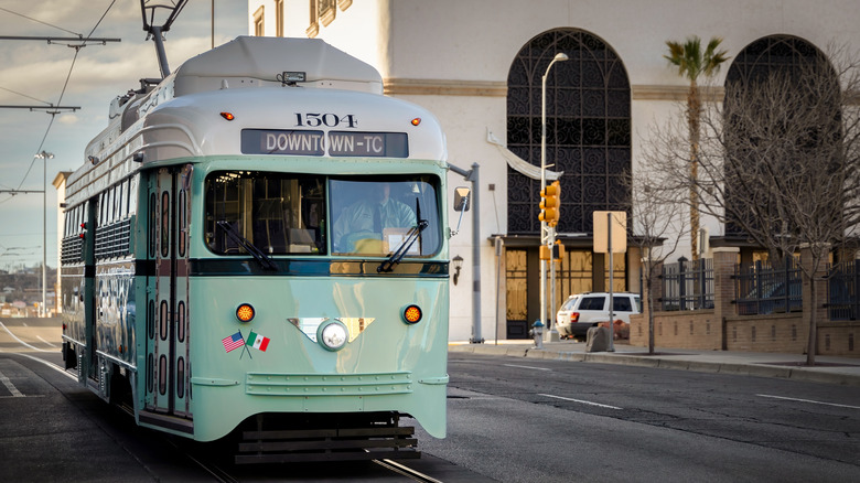 A light green trolley car moving through downtown