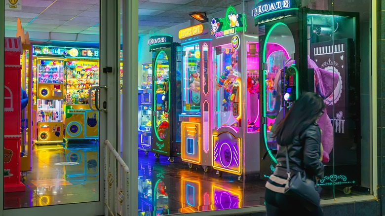 Colorful arcade machines glowing inside bright game room with claw toys, neon signs.