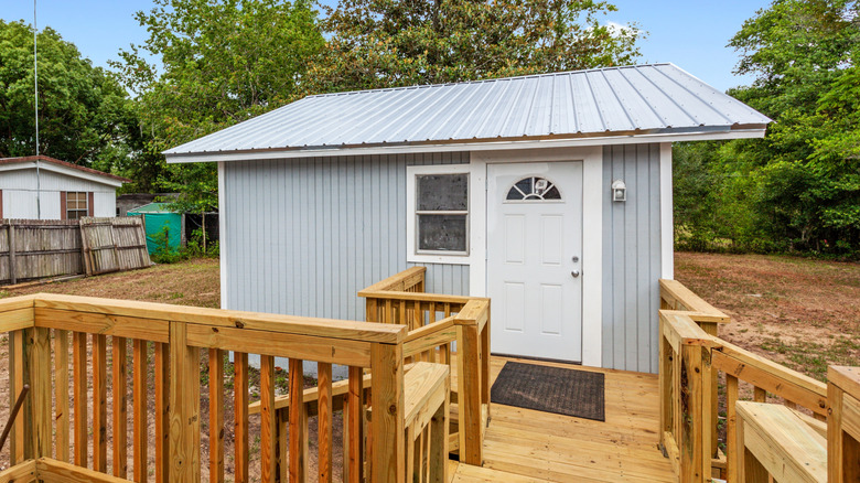 A view of a detached guest house and a deck in a property's back yard