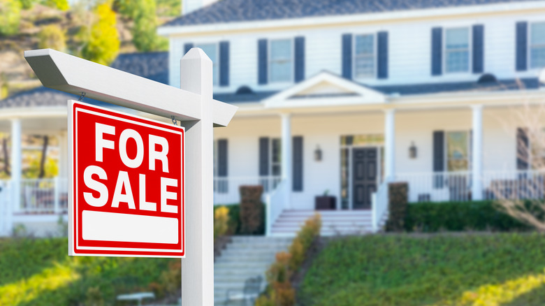A large suburban house with a for sale sign