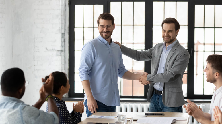 Proud boss congratulating employee and shaking hands
