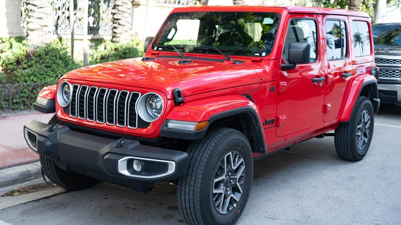 Red Jeep Wrangler parked next to a curb.