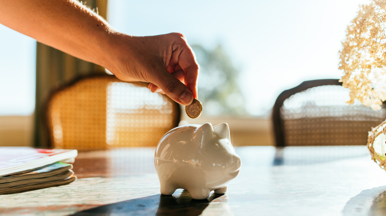 Woman putting savings in a white piggy bank