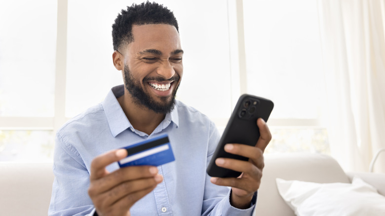 Happy excited Black bank customer man celebrating financial profit