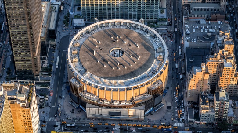 Aerial view of Madison Square Garden surrounded by high-rise buildings, pedestrians, traffic, and yellow taxis
