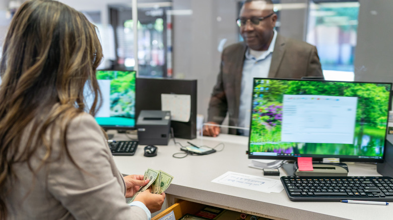 A bank teller counts cash for a customer