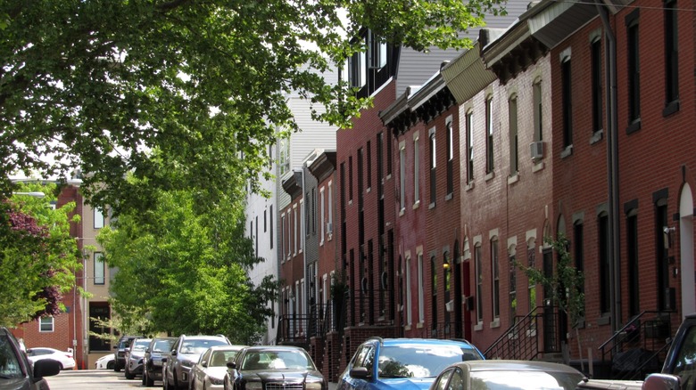 Townhomes and apartment buildings on a nice street with trees and cars lining it in Philadelphia.