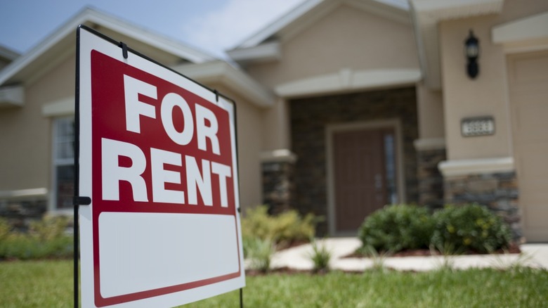A for rent sign in the yard in front of a house.