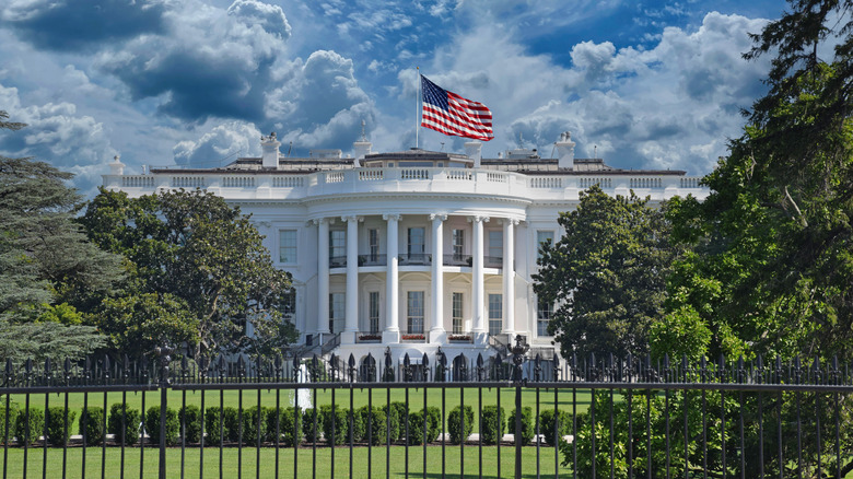 The White House behind an iron fence with a U.S. flag on top at full mast