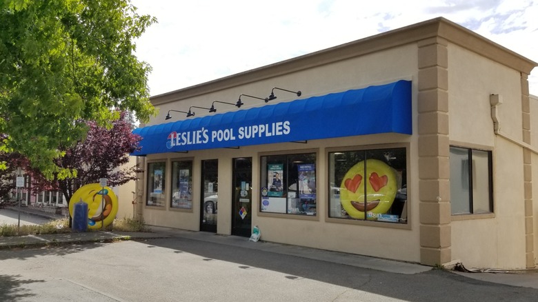 Leslie's Pool Supplies storefront with a blue awning and large yellow emoji pool floats on display