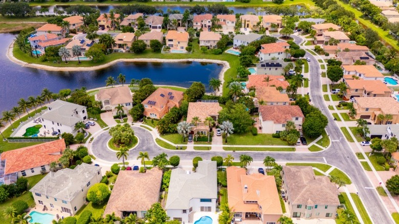 Aerial view of single family homes surrounded by trees and water in a nice neighborhood.