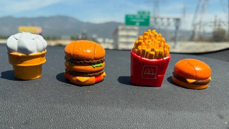 A row of four McDonald's Changeables toys on a car dashboard.