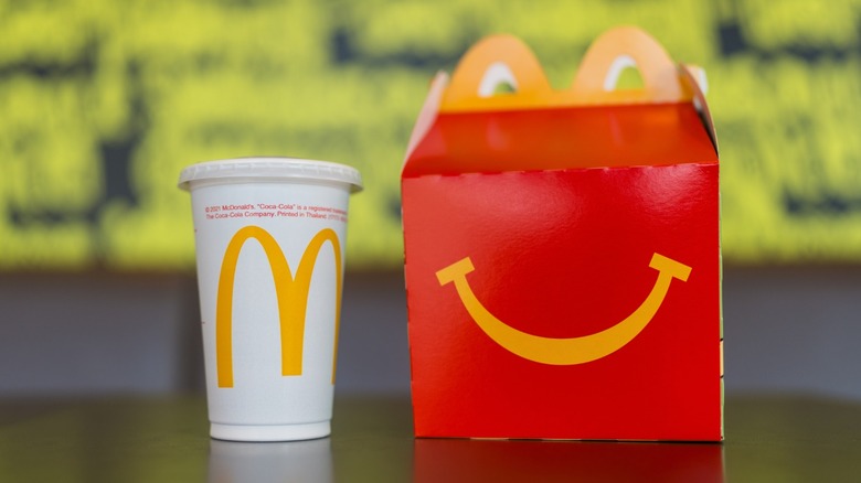 A McDonald's Happy Meal box sitting on a counter next to a small drink.