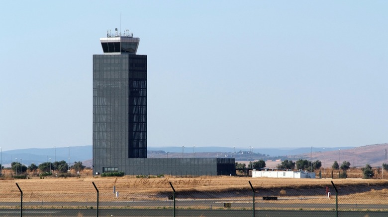 The abandoned control tower and runway of Ciudad Real International Airport behind a fence in central Spain.