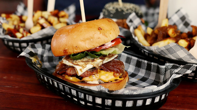 Close up image of a burger served next to two orders of fries