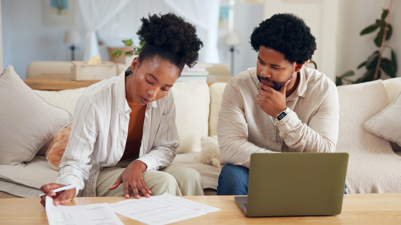 A couple reviews their financial records to save for retirement.