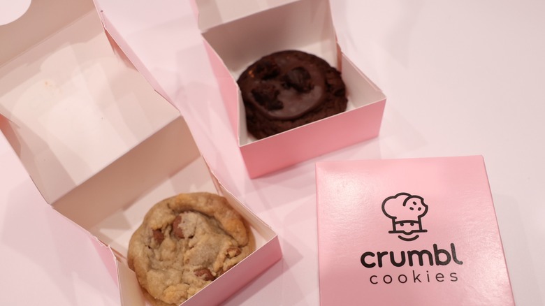 Individual Crumbl cookies on display in the company's trademark pink boxes.