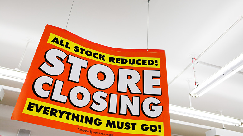 Sign reading "Store Closing" hanging from retail store ceiling