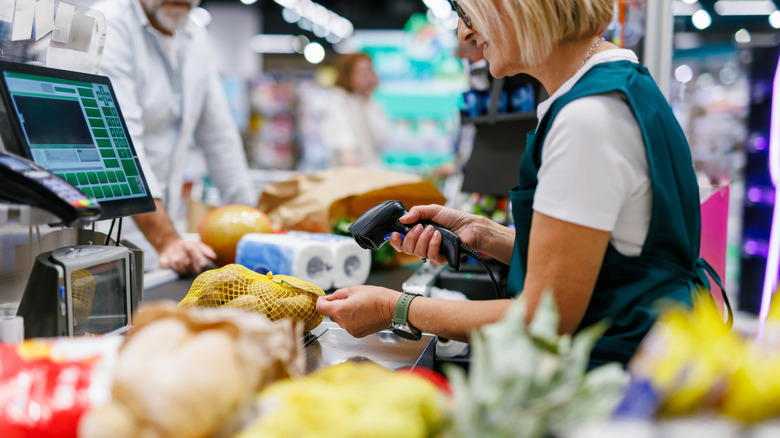A grocery store clerk ringing up items at a cash register.