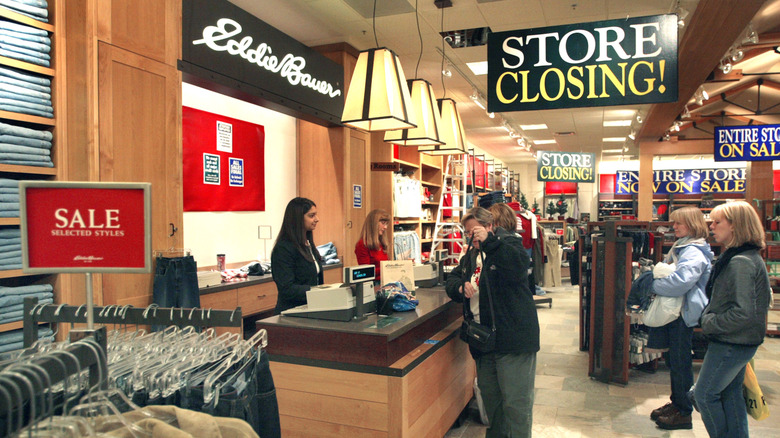 Women standing in line at an Eddie Bauer store with "Store Closing" signs visible.
