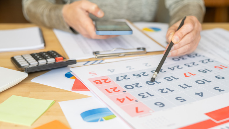 Person calculating figures with calendar