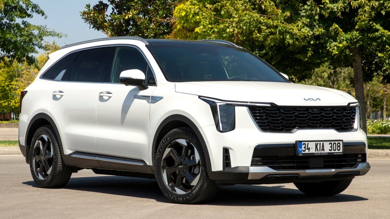 White Kia Sorento SUV parked on a sunny road with trees in the background