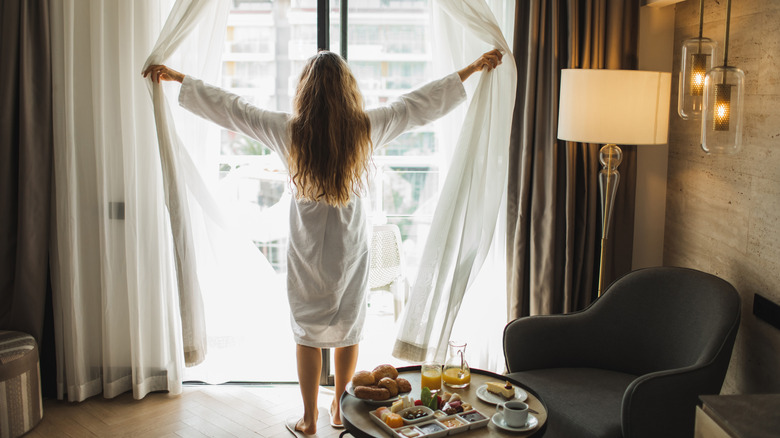 woman opening balcony curtains