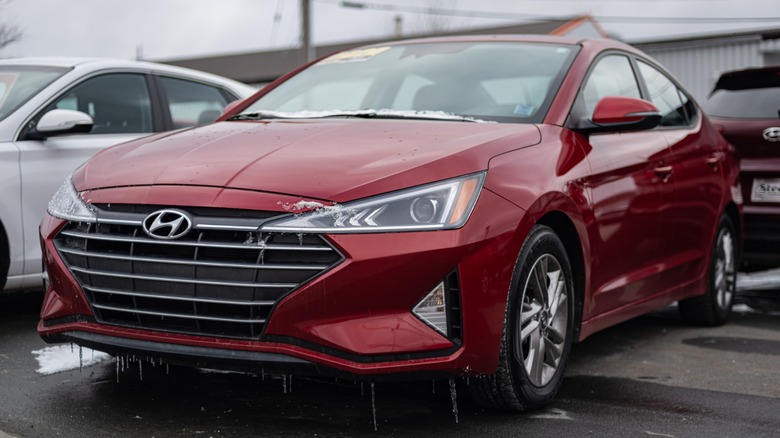 Red Hyundai sedan parked in a snowy car lot, with icicles hanging from its front bumper and grille