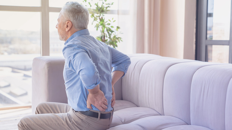 Older man on a couch with back pain