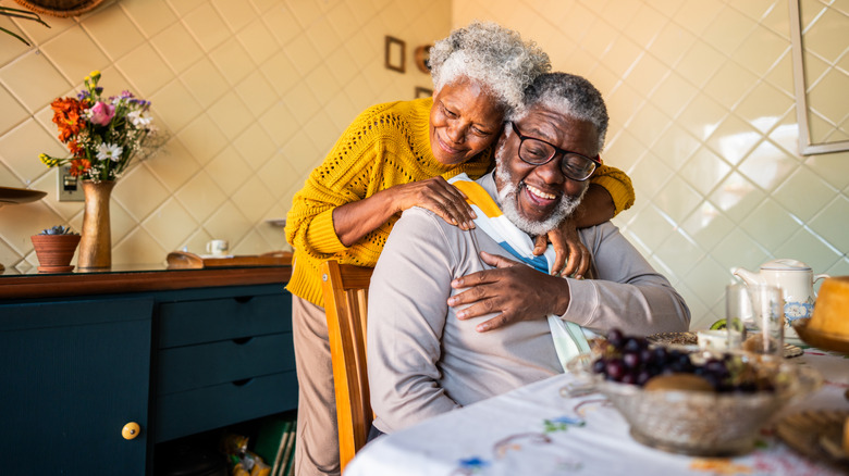 Older couple hugging by a dinner table