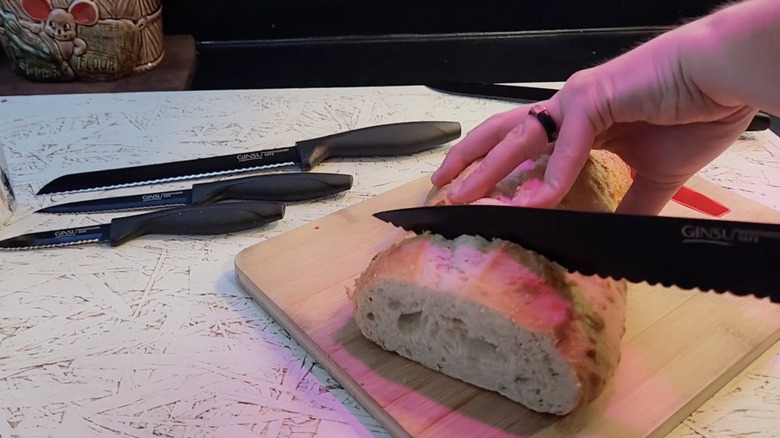 A man testing out his Ginsu knives on a loaf of bread