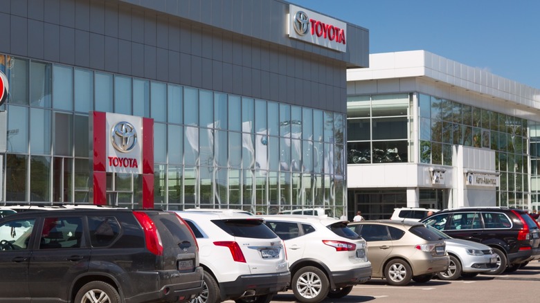 New cars parked outside of a Toyota dealership on a sunny day.