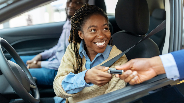 woman taking key from car salesman