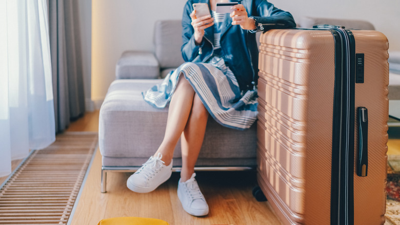 person sitting with credit card and suitcase