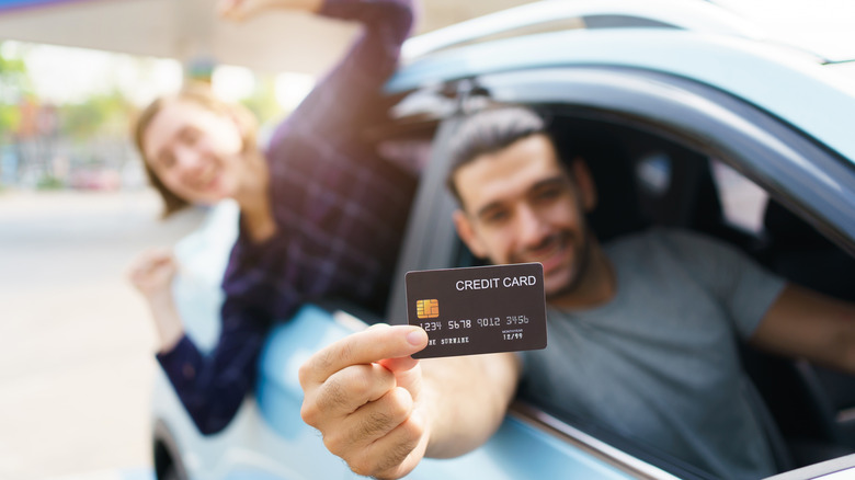 person holding credit card out of car window